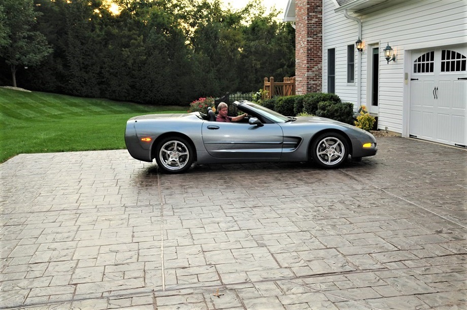 silver convertible car parked on a stamped concrete driveway in front of a house