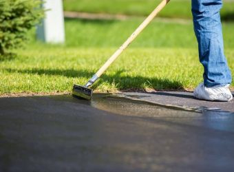 man resurfacing the driveway with a tool