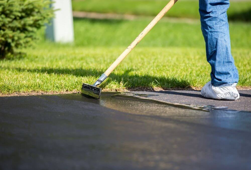 man resurfacing the driveway with a tool