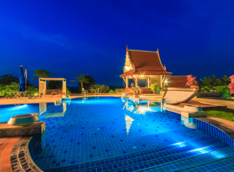 view of a concrete pool deck at night with elegant lighting illuminating the area