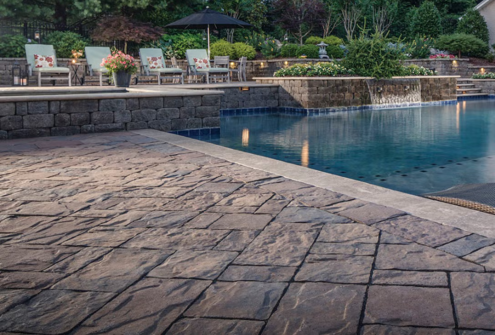 concrete pool deck with chairs and garden beside the swimming pool