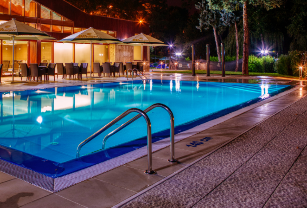 nighttime swimming pool with outside chairs and umbrella