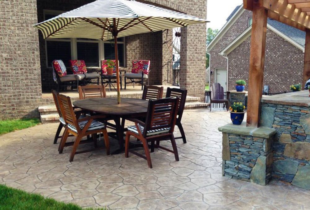 Outdoor patio with table, chairs, umbrella, and stamped flooring.
