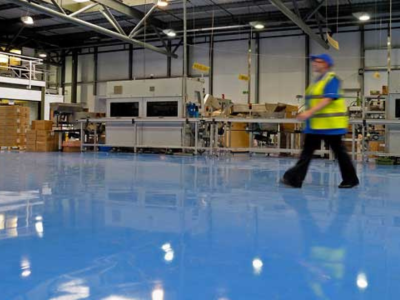 Industrial warehouse flooring in a manufacturing facility with durable epoxy or polyurea coating designed for heavy-duty performance and safety.